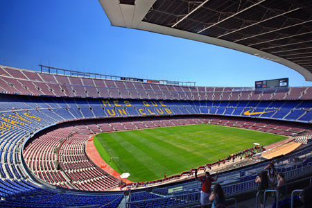 De día, se ve el interior del estadio desocupado, con sus gradas rojas y azul en el que hay turistas tomándose fotos