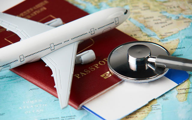Sobre un mapa hay un pasaporte con un voucher, un avion miniatura y un estetoscopio