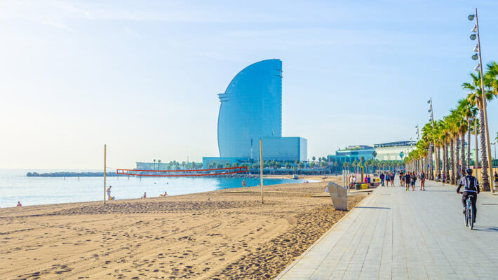 Panorámica de la Playa La Barceloneta desde el mar, al fondo se ven algunos playistas, palmeras y edificios 